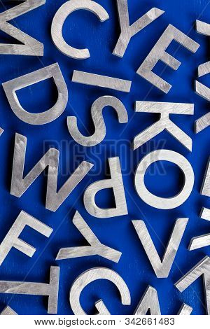 Abstract Flat Background Of Silver Metal English Alphabet Characters On Blue Background.