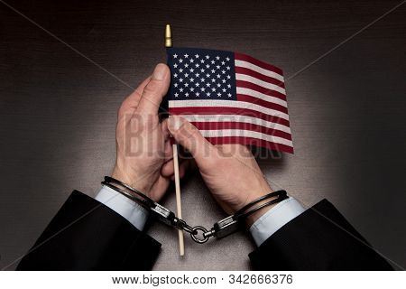 The Hands Of A Businessman In Handcuffs Holding An American Flag 2
