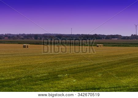 Straw Bales On Farmland With Blue Cloudy Sky