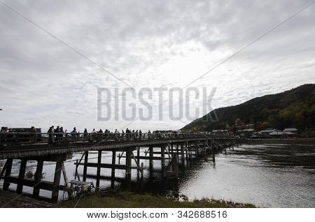 Kyoto, Japan-26 Nov, 2019: Togetsu-kyo Bridge Over Katsuragawa River With Colourful Forest Mountain 