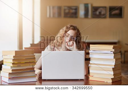 Portrait Of Sleepy Hard Working Sitting At Library, Closing Eyes, Yawning, Using Her Laptop During S