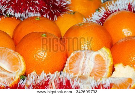 Bright Juicy Tangerines In A Christmas Shiny Tinsel, The Concept Of A Winter Holiday And A Large Har