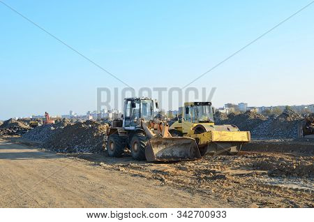 Soil Compactor And Wheel Loader At Construction Site. Vibration Single-cylinder Road Roller Leveling