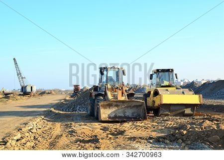 Soil Compactor And Wheel Loader At Construction Site. Vibration Single-cylinder Road Roller Leveling