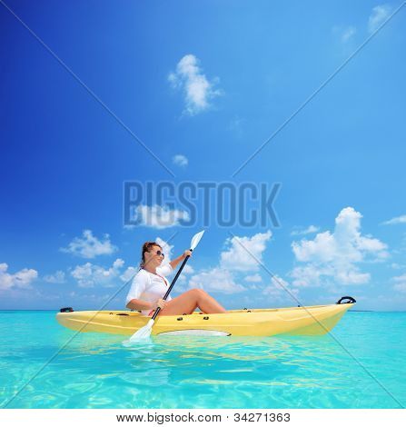 Eine junge Frau im gelben Kajak Kajak in der Nähe ein Kuredu Island, Malediven, Lhaviyani atoll