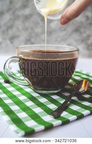 Transparent Cup Of Coffee With Pouring Condensed Milk