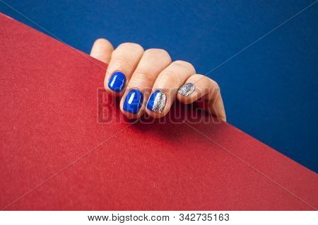 Young Womans Hand With Beautiful Manicure On Blue And Red Background With Copyspace. 2020 Color Tren