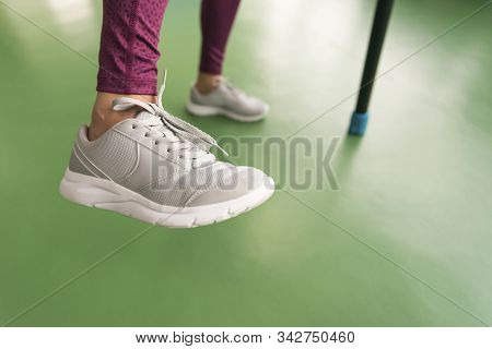 Legs Of Young Fit Woman Doing Exercise With Bodybar In Gym