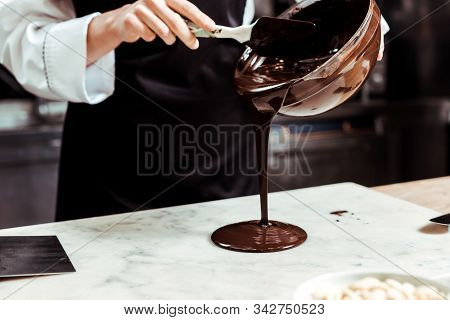 Cropped View Of Chocolatier Pouring Melted Chocolate On Marble Surface