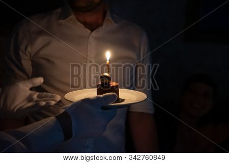 Birthday Cake With A Single Candle Being Presented By A Waiter Or Server