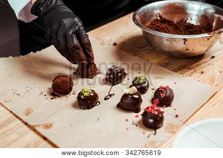 Cropped View Of Chocolatier In Black Latex Glove Preparing Truffle Candies Near Chocolate Balls