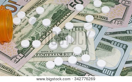 Prezcription Medication On Top Of Us Currency Of One Hundred And Fifty Dollar Bills Spilled Out Of A