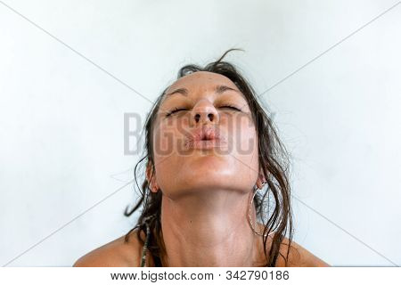A Close Up Portrait Of An Exhausted And Sweaty Yoga Participant, With Closed Eyes As She Breathes Ou
