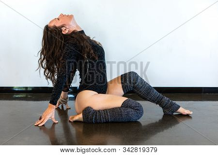 An Empowered Caucasian Woman Is Seen In A Mindful Yoga Posture Against A White Wall During A Vinyasa