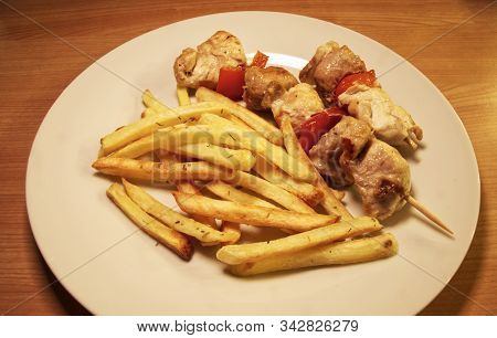 Chicken Meat On Wooden Skewers On White Plate With French Fries.
