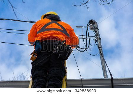 A Low Angle Shot Of A Domestic Service Provider Engineer Installing New Fiber Optic Cables To A Resi