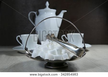 Sugar Cubes In Metal Vintage Sugar  Bowl With Sugar Tongs And Cups With Coffee Or Tea Pot.