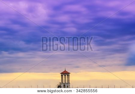 Magnificent Sunset With Dramatic Thunderclouds. In The Foreground Is A Tower.sunset Over Water Magni