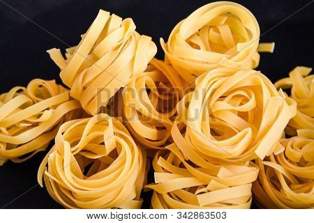 Pasta Alluovo, Tagliatelle Pasta, Round Balls Of Raw Pasta On Black Background, Close Up Of A Raw Dr