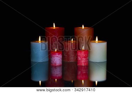 Group Of Colored Lit Candles With Reflection