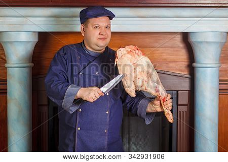 Half Legth Shot Of Thoughtful Male Chef, Holds Very Big Red Raw Piece Of Meat, Needs To Chop For Pre