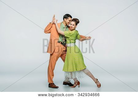 Stylish Dancers Holding Hands While Dancing Boogie-woogie On Grey Background
