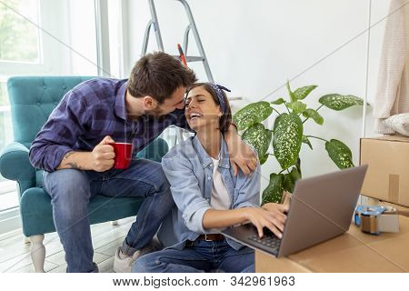 Beautiful Young Couple In Love Moving In Together, Drinking Coffee And Having Fun While Searching Th