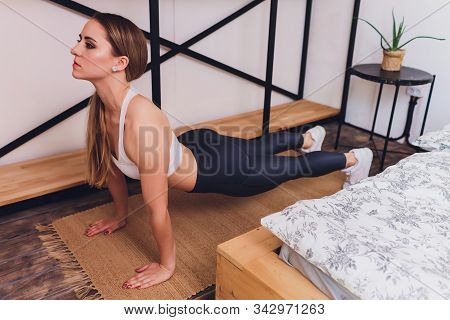 Attrctive Fitness Woman Doing Stretching Exercises At Home, As Part Of A Healthy Lifestyle Without G