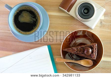 Notebook, Camera,  Coffee, Chocolate Cake On Wooden Background