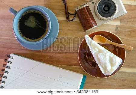 The Notebook, Camera, Coffee, Coconut Cake On Wooden Background