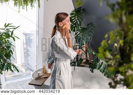 Side View Of Young Beautiful Woman Exfoliating Facial Skin With Mask Remover Cellulose Face Sponge, 