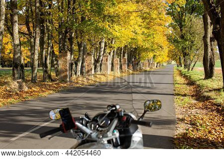 A First-person Motorcycle Journey. Autumn Road Leaves Are Yellow, Green And Orange. Selective Focus.