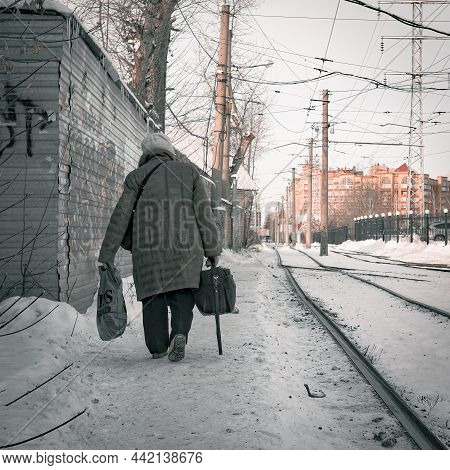17th Of November 2021, Russia, Tomsk, Old Woman Go Along Rialway With Bags
