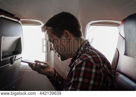 Man Speakerphone Call On Phone In Seat Of Passenger On Board Of Plane.