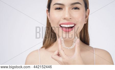 Young Smiling Woman Holding Invisalign Braces In Studio, Dental Healthcare And Orthodontic Concept