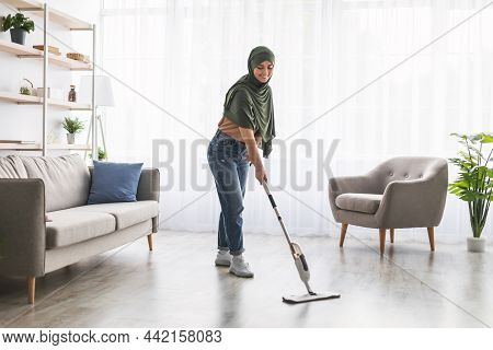Muslim Woman Cleaning Floor With Spray Mop In Living Eoom