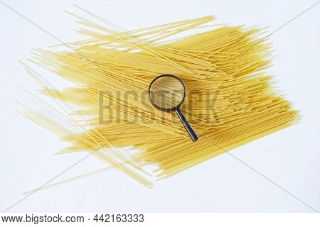 Durum Wheat Spaghetti And Magnifying Glass On A White Plate. Concept For Research, Analysis And Exam