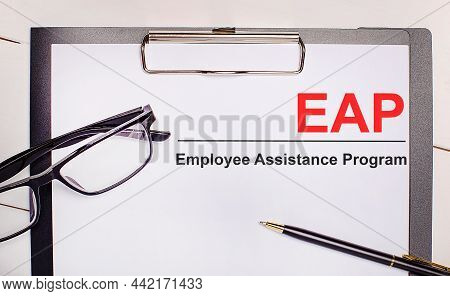 On A Light Wooden Background Glasses, A Pen And A Sheet Of Paper With The Text Eap Employee Assistan