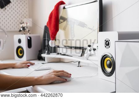 Female Hands On The Computer Table Hold A Gaming Mouse And Keyboard. A Red Santa Hat Hangs On The Mo