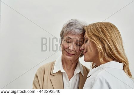 Loving Mature Mother And Grownup Daughter Hug Touch Foreheads Share Tender Close Family Moment. Cari