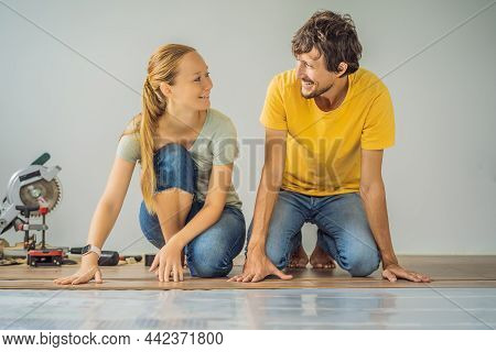 Married Couple Installing New Wooden Laminate Flooring On A Warm Film Floor. Infrared Floor Heating 