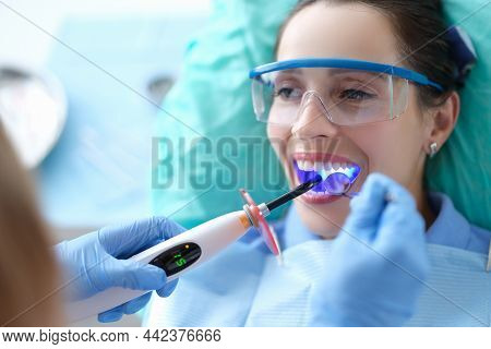 Dentist Works With Dental Polymerization Lamp In Oral Cavity. Caries Treatment Concept
