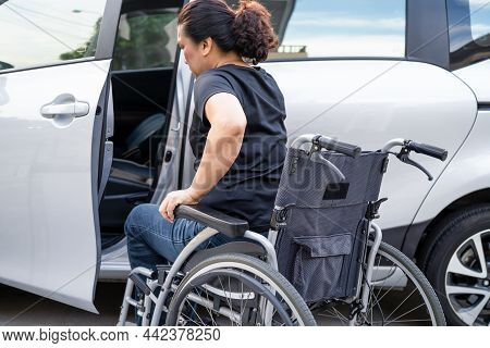 Asian Woman Folding And Lift Up Wheelchair Into Her Car. Accessibility Concept.