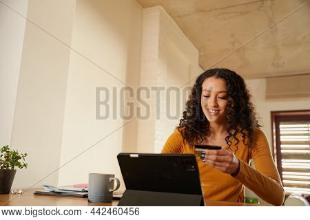 African American Female Working From Home Typing On Digital Tablet Making Online Payment With Credit