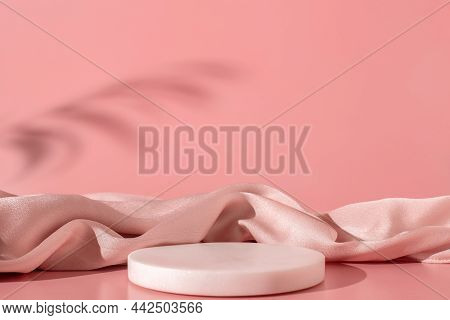 White Marble Podium On The Pink Background With Silk Fabric And Shadow Of Tropical Plant. Podium For