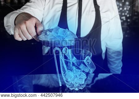 A Professional Bartender Adds Cold Ice Cubes On A Scap To A Serving Dish.