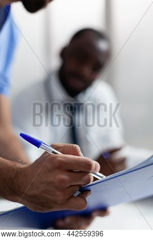 Closeup Of Man Nurse Hand Checking Illness Symptoms On Clipboard Discussing Healthcare Treatment Wit