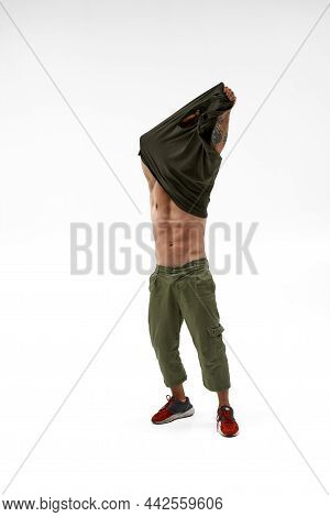 Muscular Man Taking Off Tank Top. Bearded And Bald Guy With Naked Torso And Tattoo. Modern Youth Sty