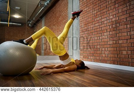 Young Slim Body  Female Athlete Exercises With Fitness Ball, Performing Glute Bridge In Fitness And 