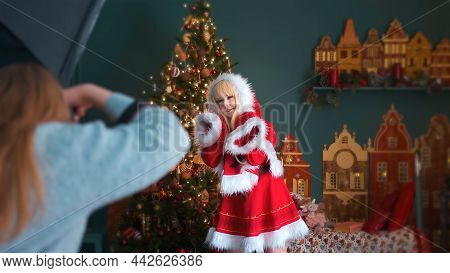 Cute Girl In A Red Costume Of The New Years Elf. Posing For The Photographer. New Year Theme